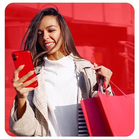 Mulher sorridente segurando sacolas de compras e celular, representando a praticidade do Cartão Besni.